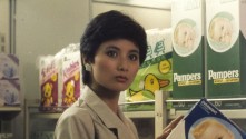 an Asian woman in the diaper section of the supermarket looks at the camera